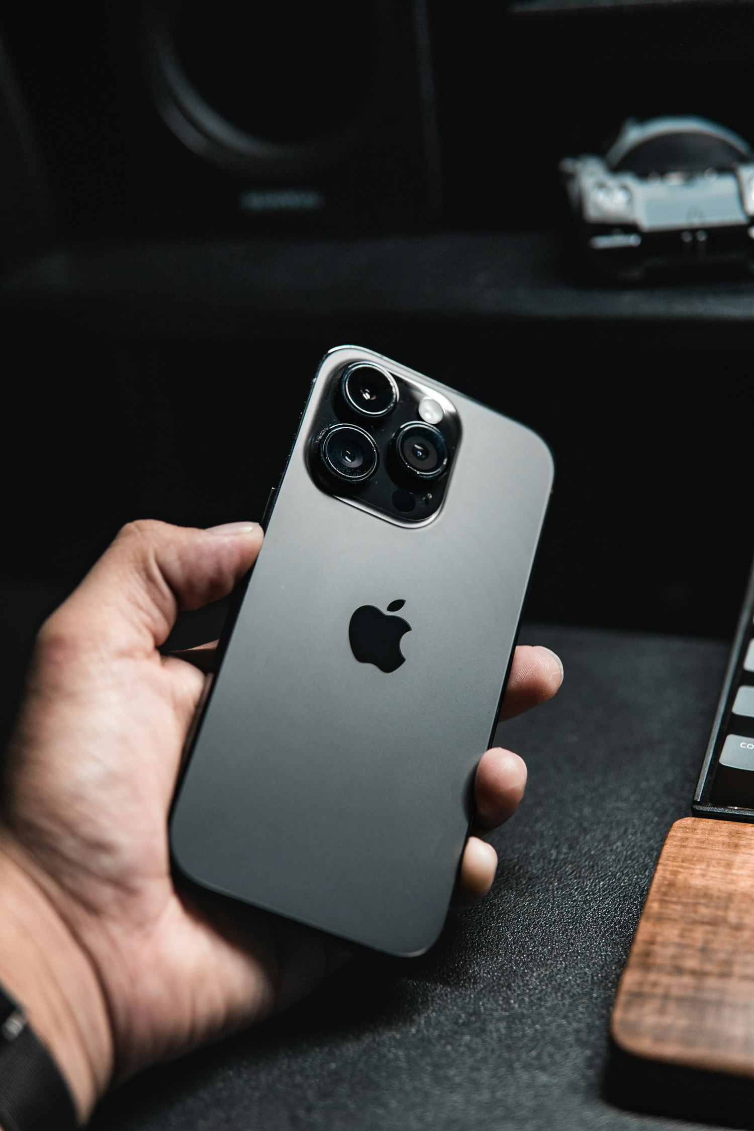 iPhone en titane tenu à la main, dos apparent.