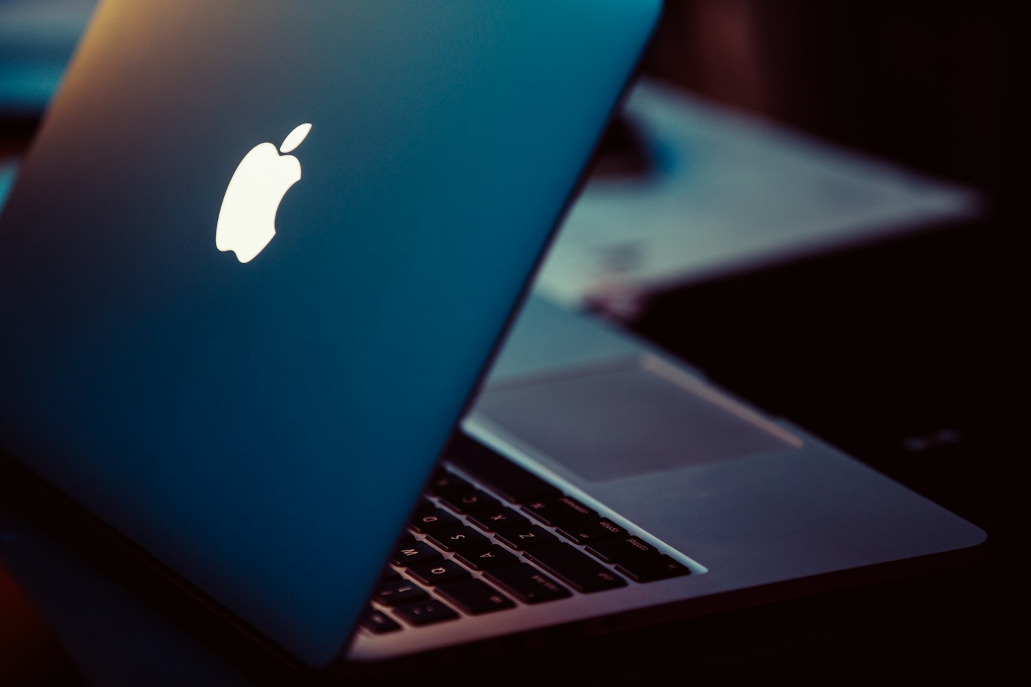 MacBook ouvert de trois quarts, lumière rasante.